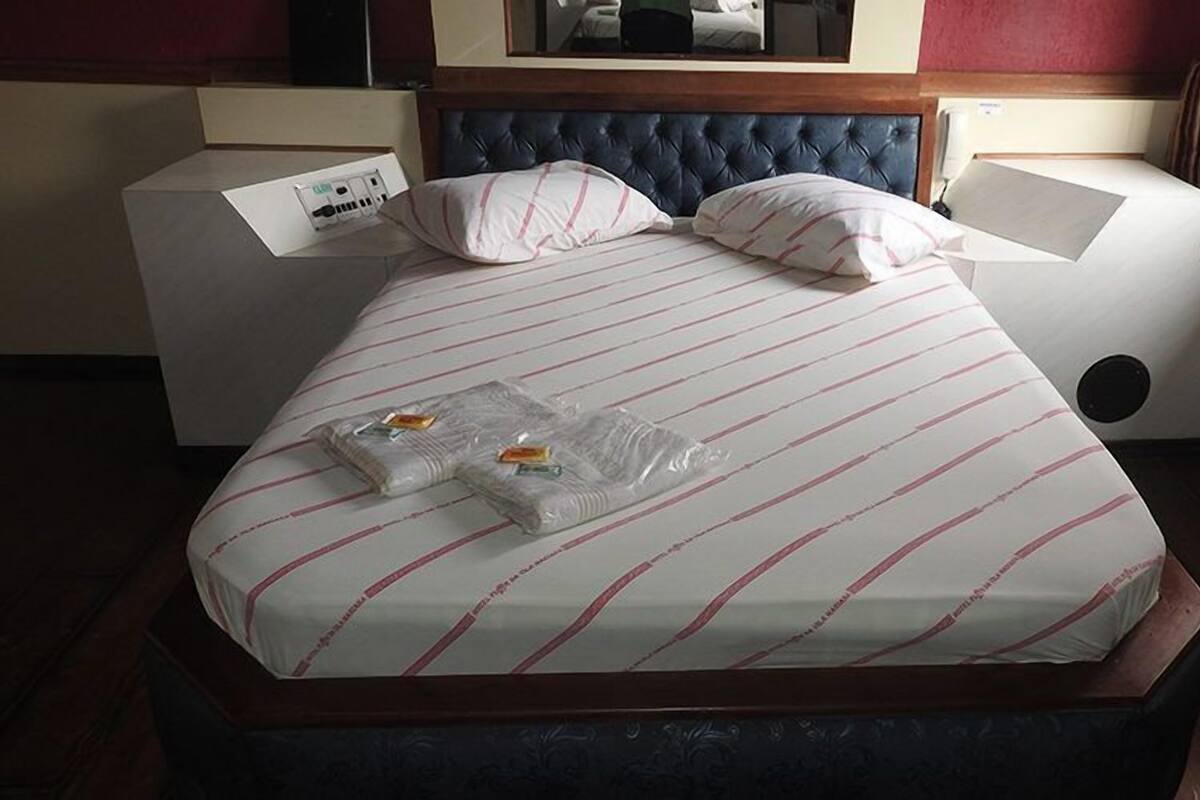 Un lit bien fait, avec une literie à rayures, deux oreillers et deux coussins emballés dans du plastique.