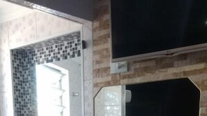 A bathroom with a tiled wall, a sink, and a shower area. - Hotel Flor da Vila Mariana (São Paulo)