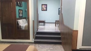 A hotel room with a bed, a wooden door, a staircase, and a small table. - Hôtel Adounia (Ouled Moussa)