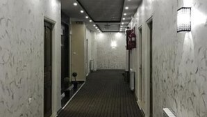 A hallway with patterned walls, a dark carpet, and recessed lighting. - Hôtel Adounia (Ouled Moussa)