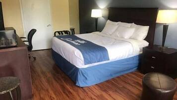Una habitación de hotel con una cama, un escritorio, una silla y una lámpara.