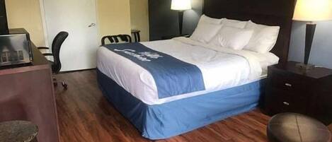 Une chambre d’hôtel avec un lit, un bureau, une chaise et une lampe.