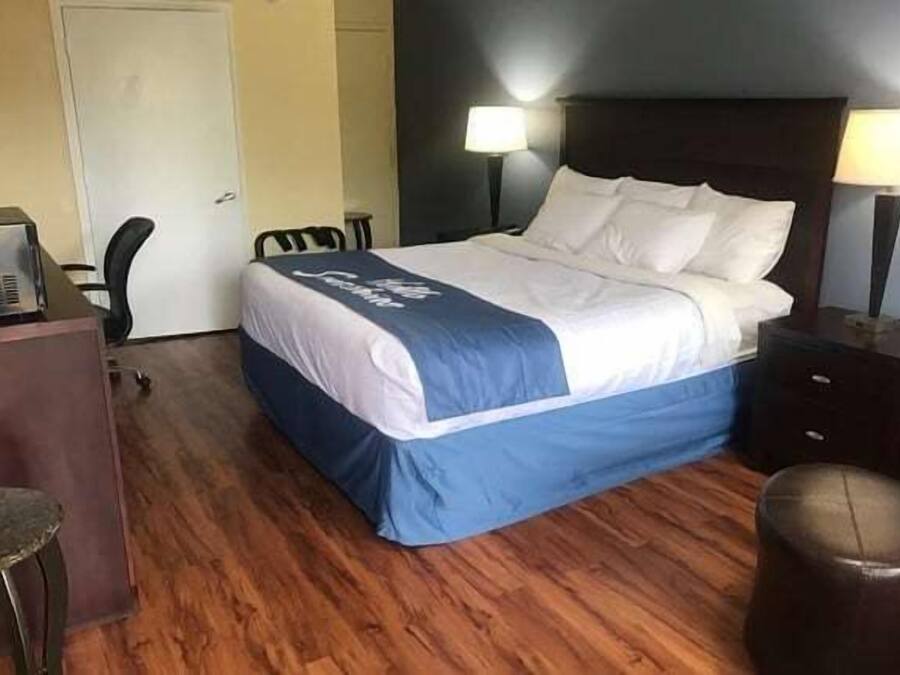 Una habitación de hotel con una cama, un escritorio, una silla y una lámpara.
