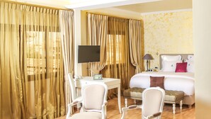 Une chambre d’hôtel équipée d’un bureau, de deux chaises, d’un lit et d’une télévision.