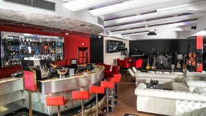 Un espace bar aux couleurs rouge et blanc, avec un téléviseur et des instruments de musique.