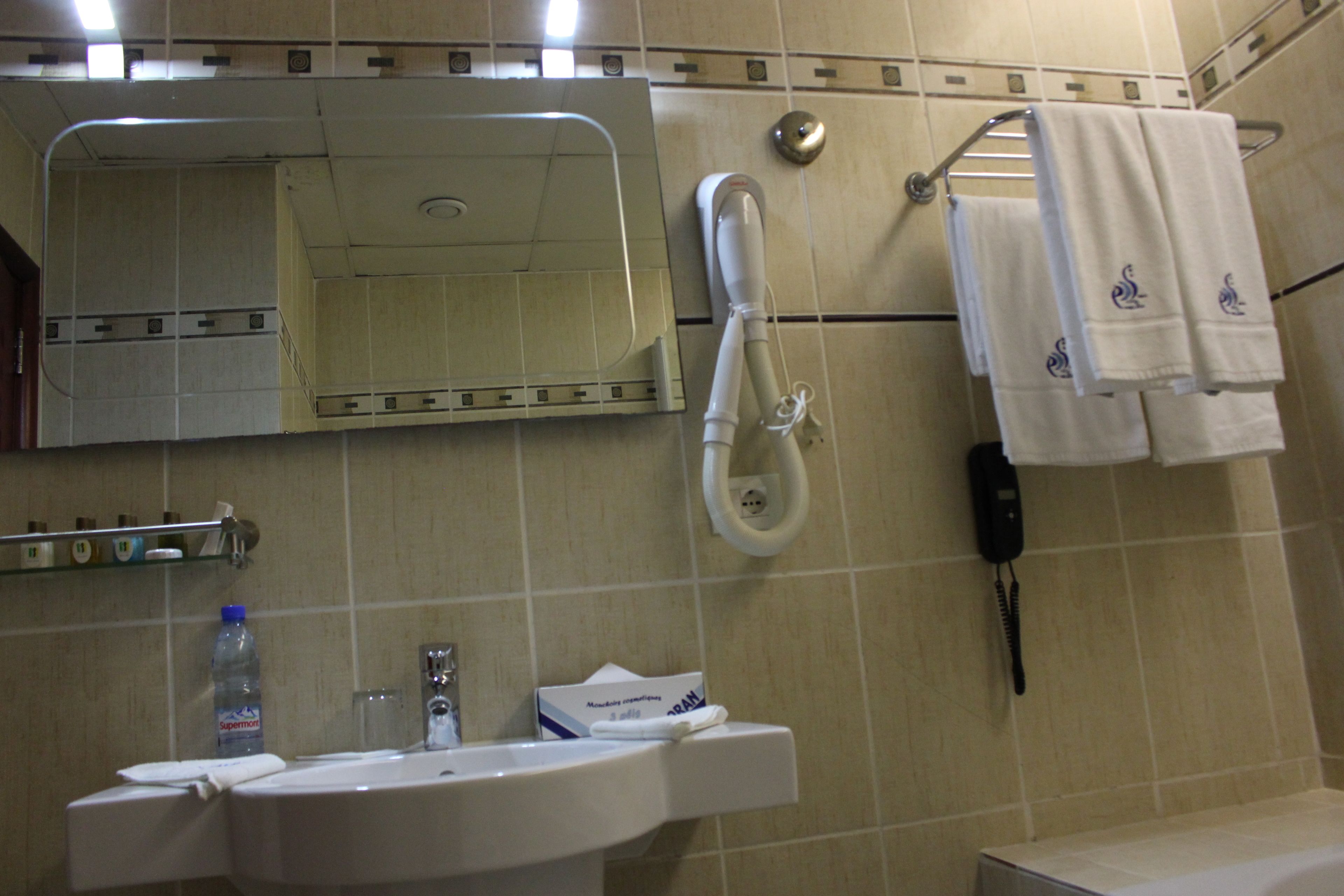 Ein Badezimmer mit Waschbecken, Spiegel, Handtuchhalter und Telefon.