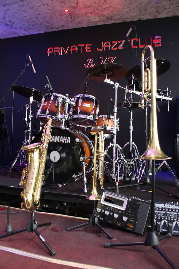 A drum set with Yamaha branding, a saxophone, and a microphone stand. - Particular Destiny Suites (Douala)