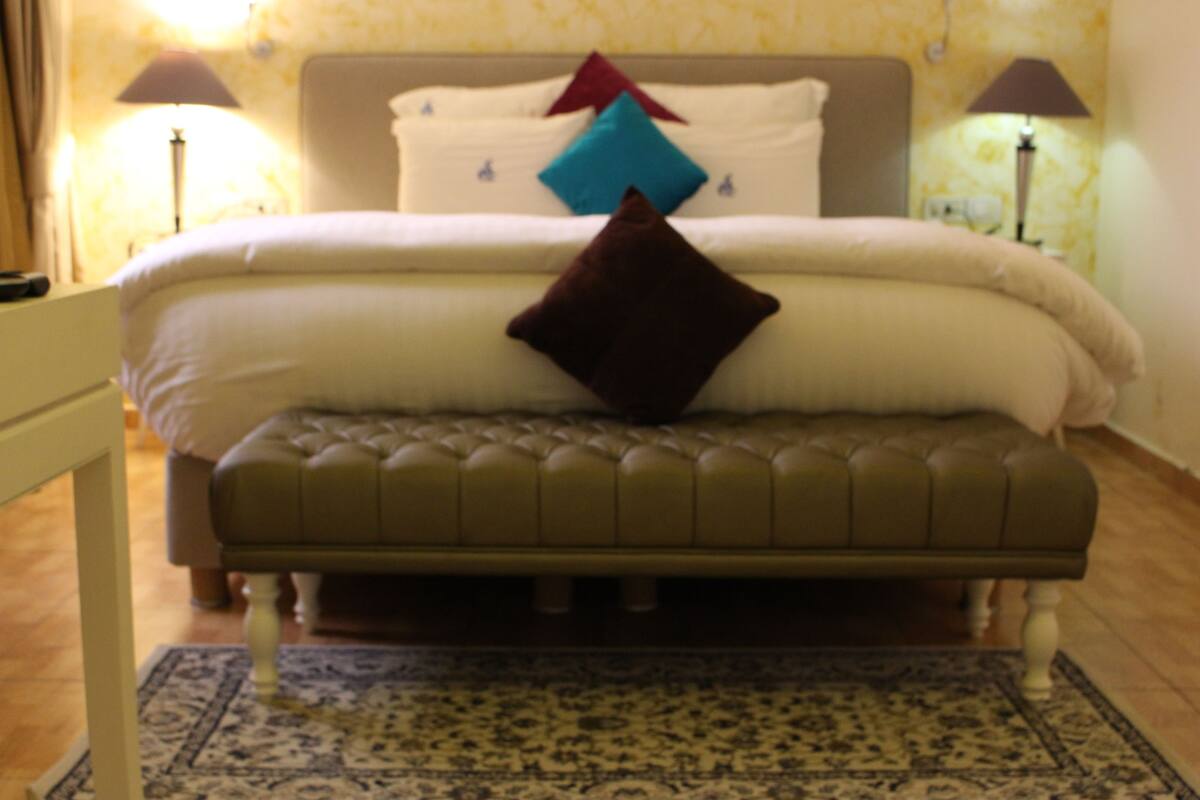 A bedroom with a bed, a bench, and two lamps.