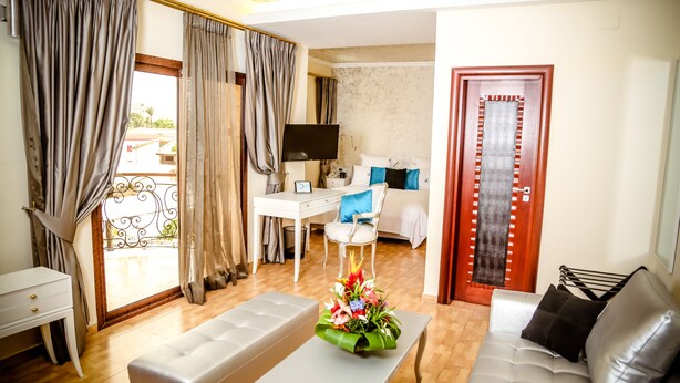 Une chambre d’hôtel avec un balcon, un bureau, un lit, un canapé et une télévision.