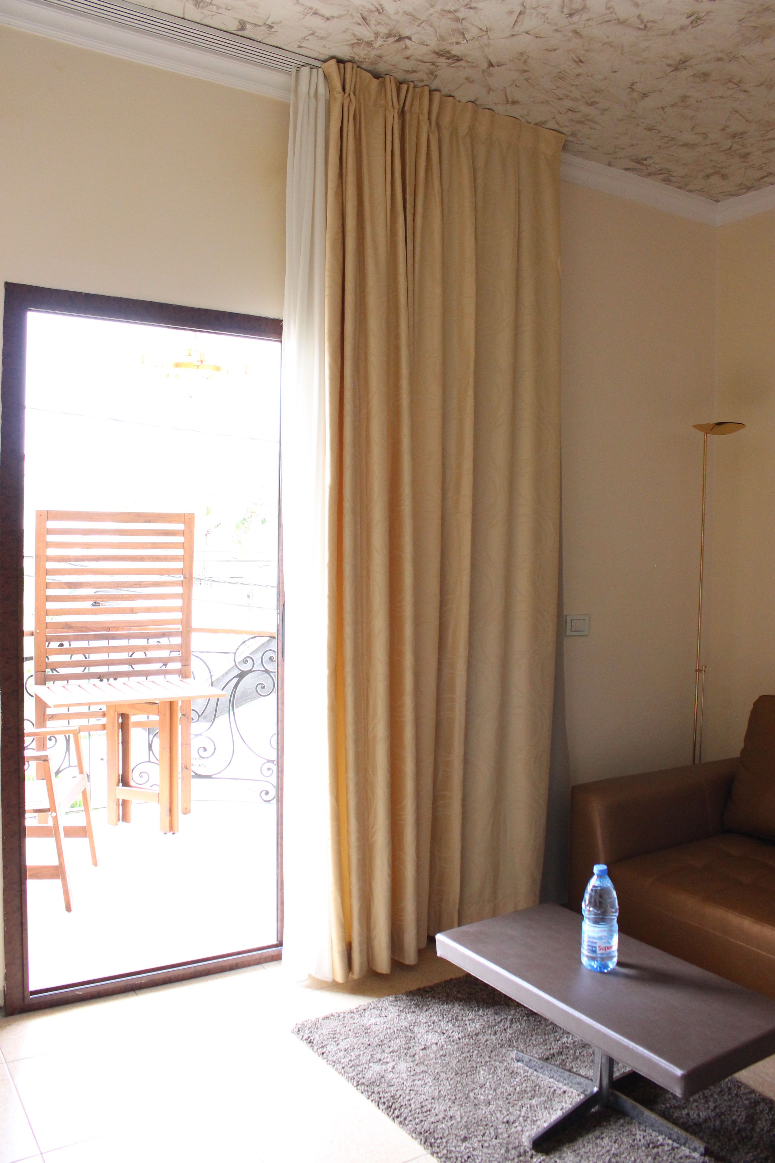 A living room with a sofa, a coffee table with a water bottle, a sliding glass door, and a floor lamp.