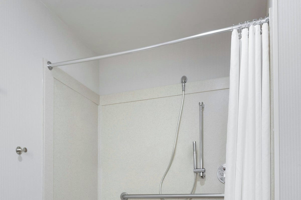 A small, enclosed shower area with a white showerhead, a handheld showerhead, and a grab bar.