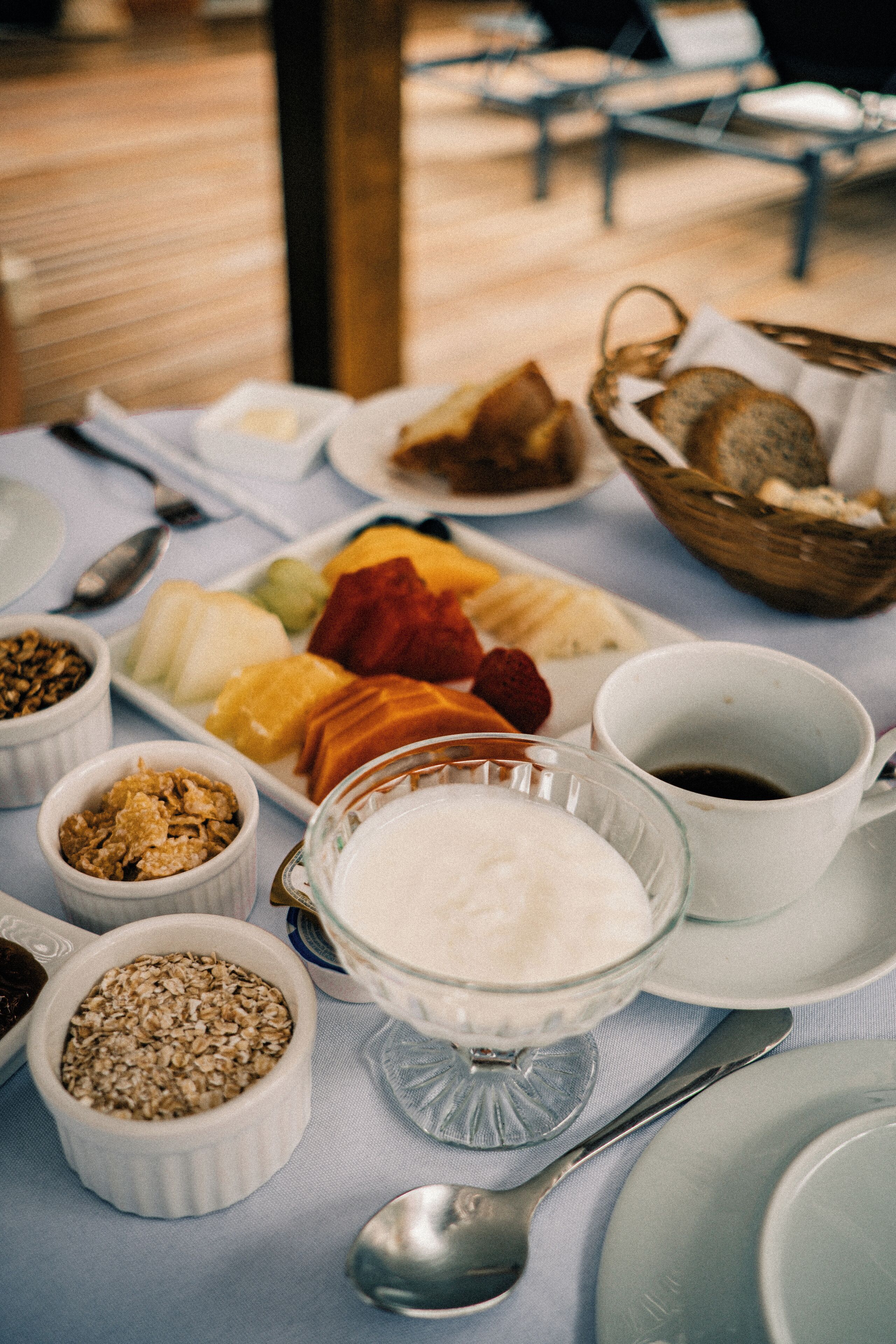 A breakfast table with various food items and utensils.