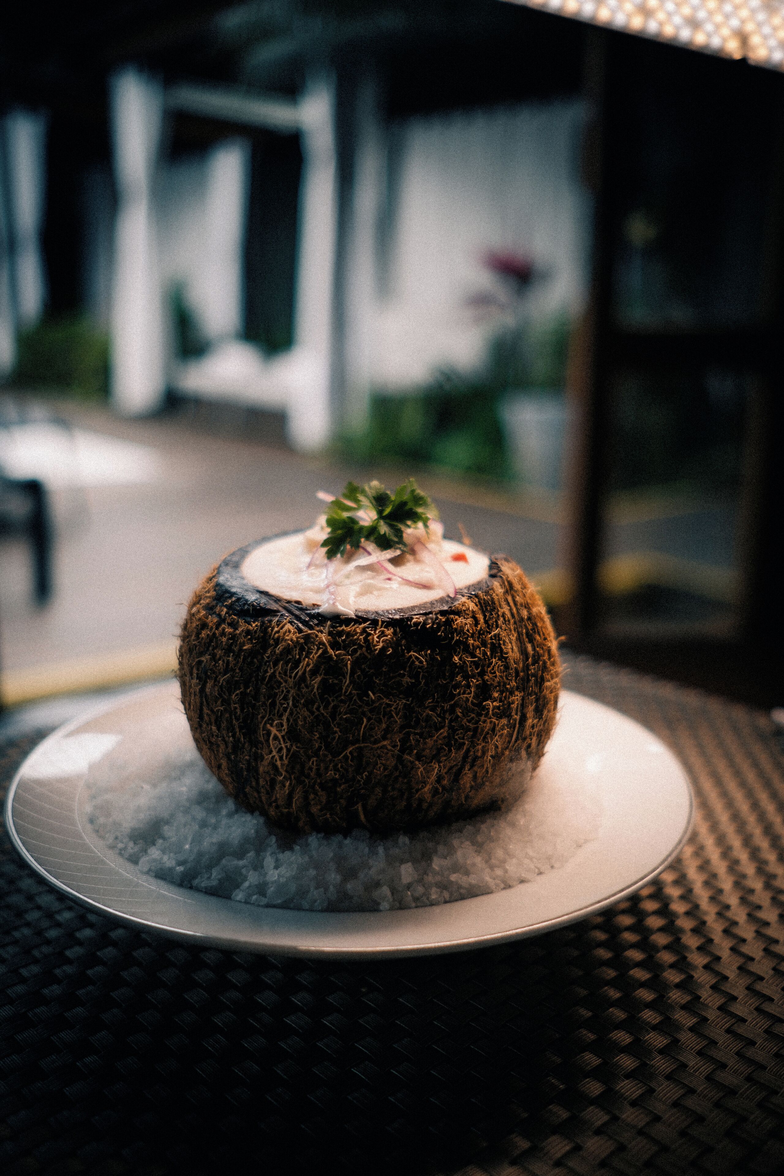 A round, textured object on a plate with a garnish, placed on a textured surface.