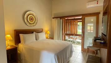 Una habitación de hotel con una cama grande, techo de madera, un plato decorativo en la pared, televisión y una pequeña mesa con lámpara.