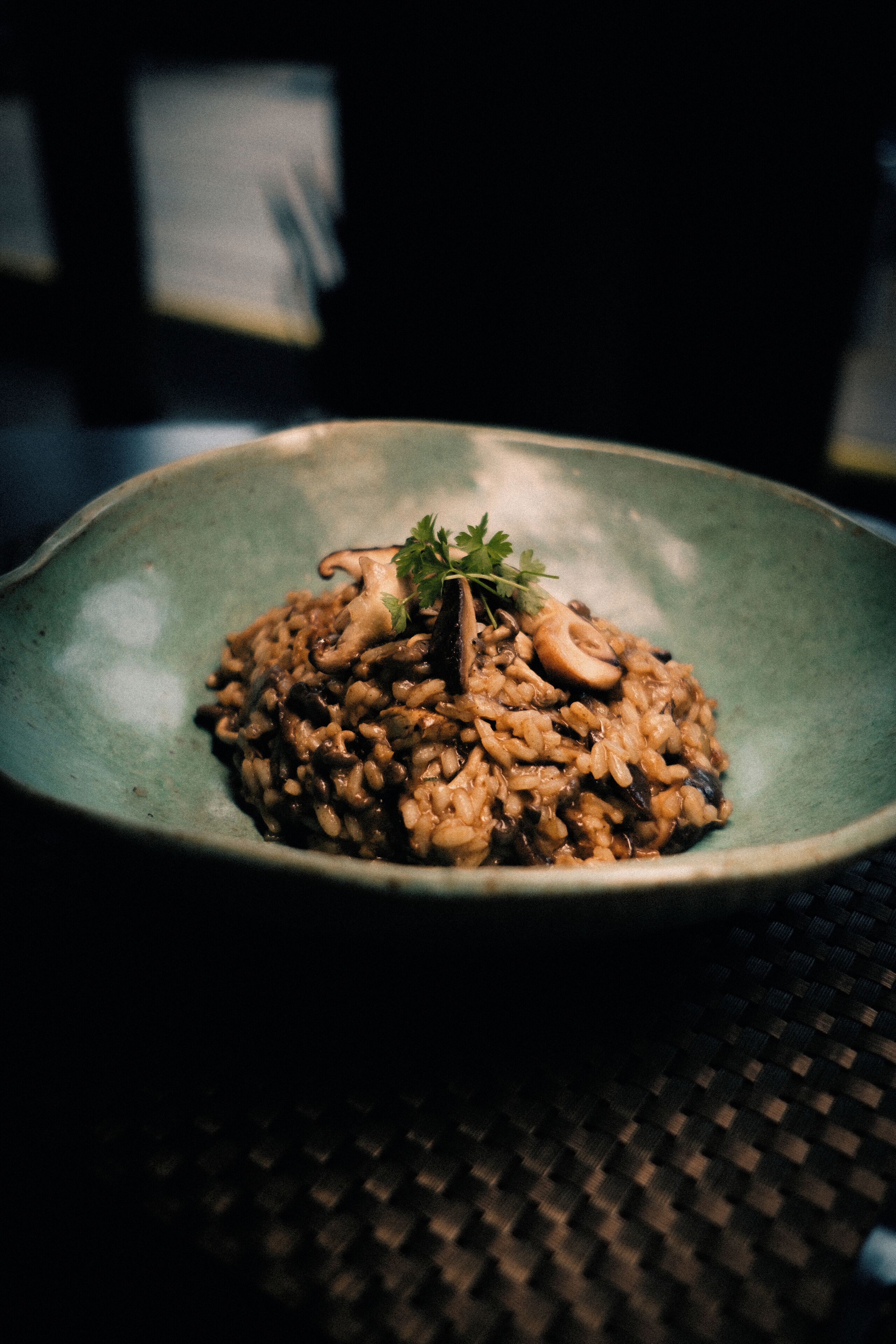 A bowl of mushroom risotto on a textured table.