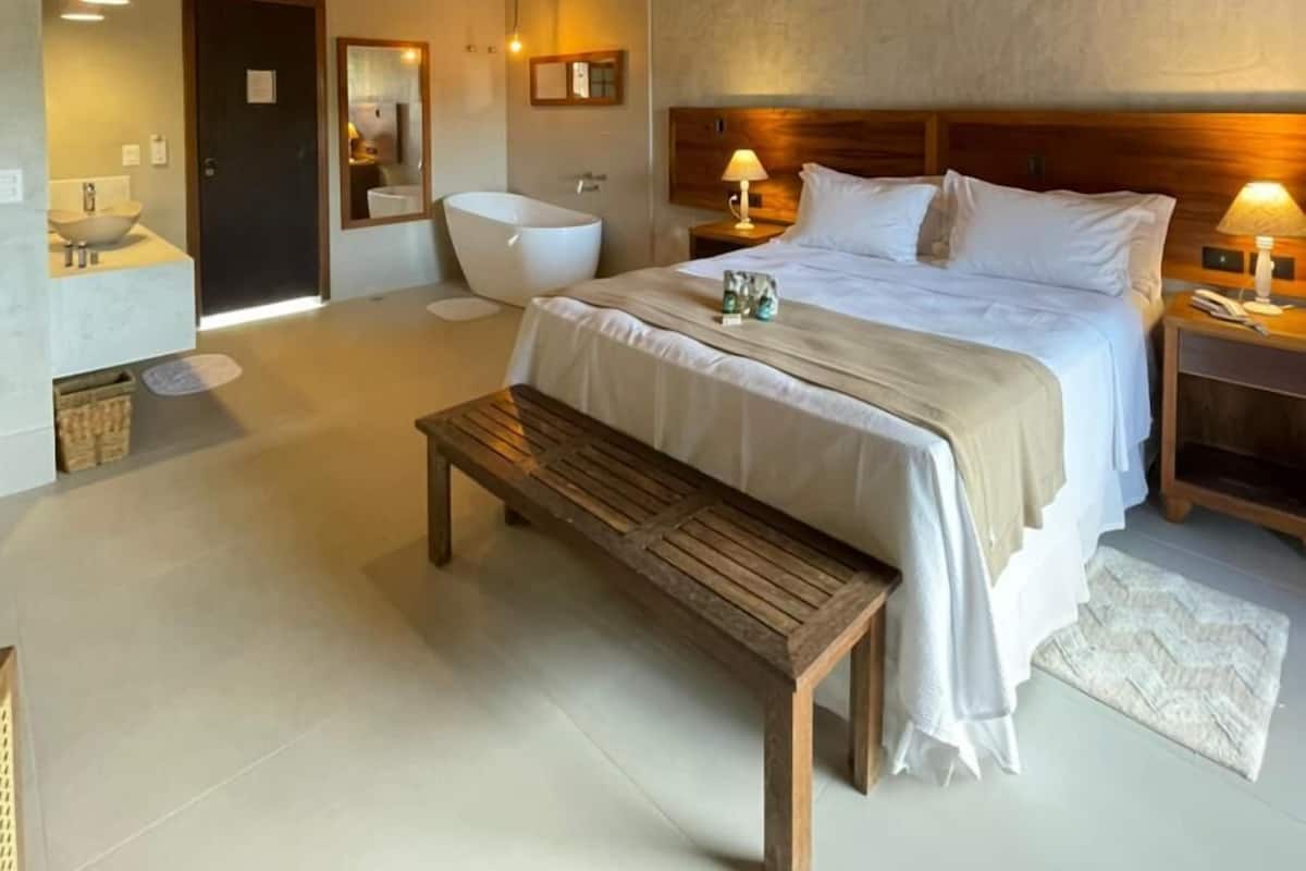 Une chambre spacieuse avec un grand lit, un plafond en bois et un banc.