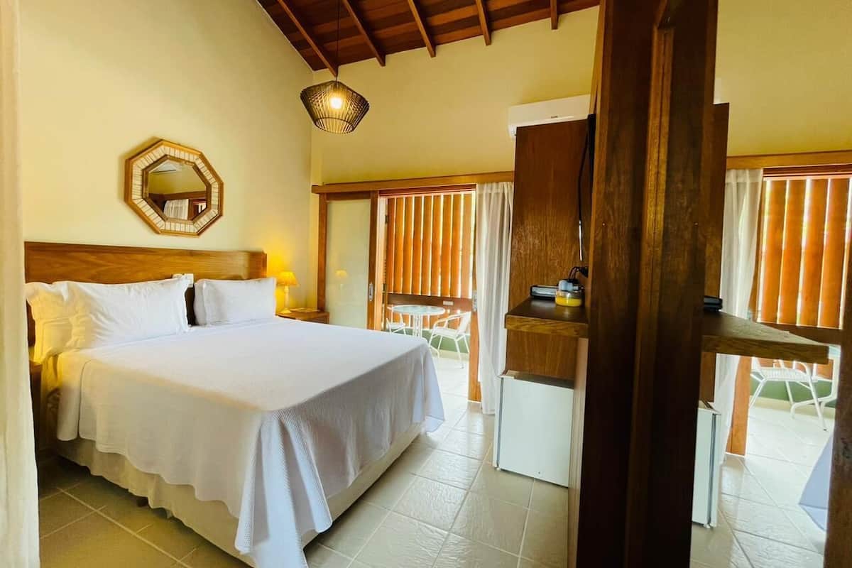Une chambre d’hôtel avec un lit, un plafond en bois, une petite table avec une lampe et une vue sur l’extérieur.