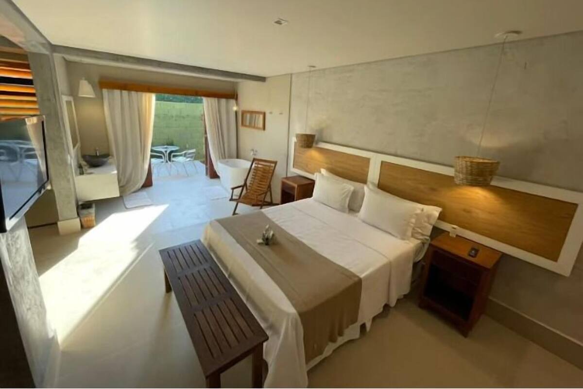 Une chambre d’hôtel moderne avec un grand lit, une télévision, un banc en bois et une vue sur l’extérieur.