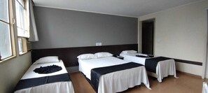 A hotel room with two single beds, a window, and a door.