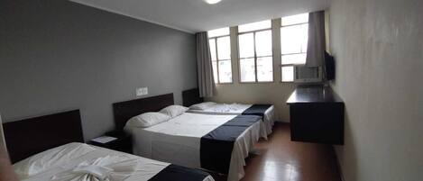 A hotel room with two beds, a TV, and a window with curtains.