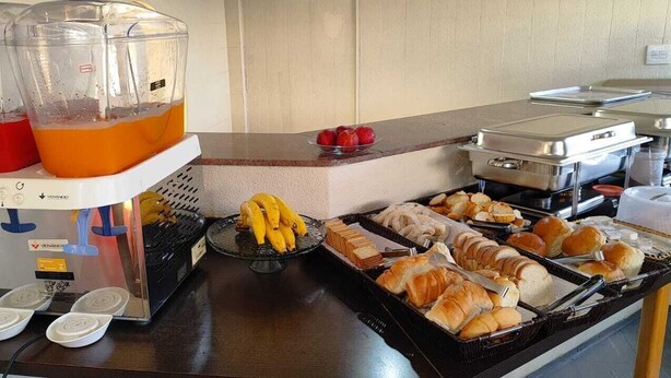 A buffet setup with a beverage station, fruits, and various baked goods. - Hotel La Rocca, Goiânia  (Goiania)