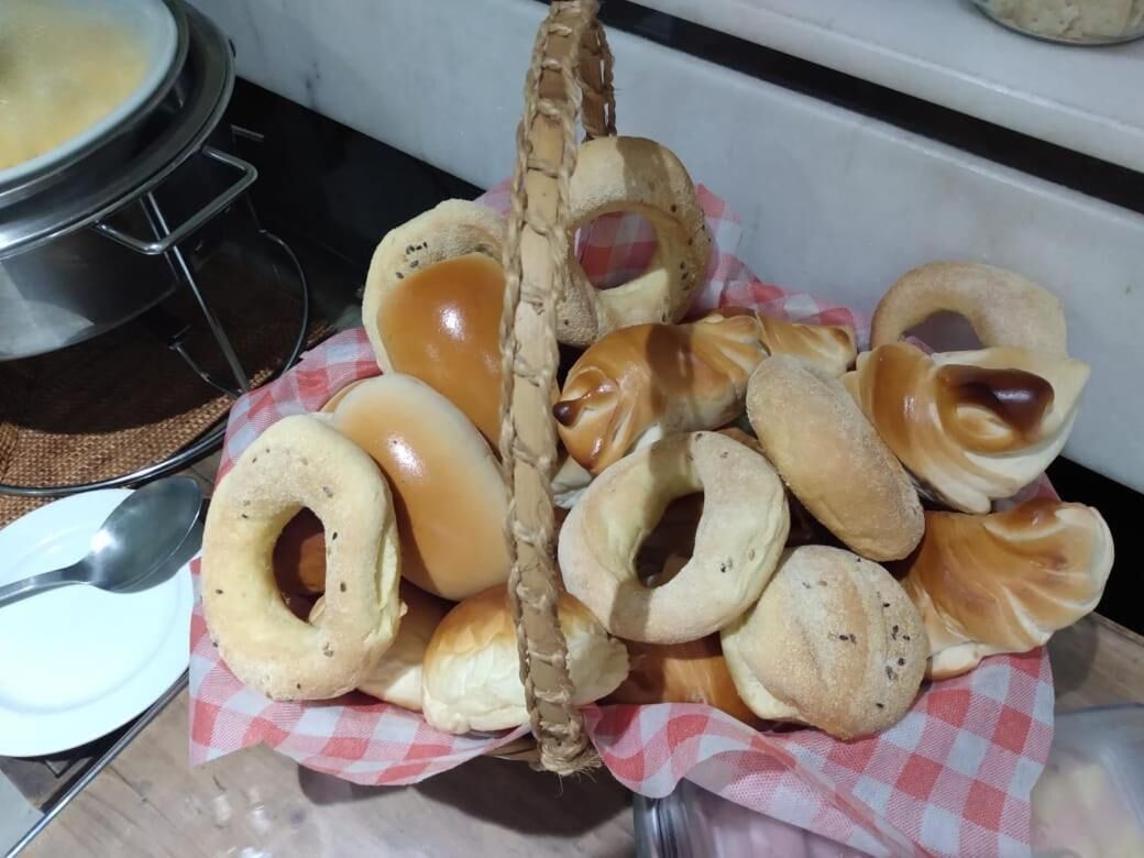 Una cesta con bagels variados y queso crema sobre un mantel a cuadros.