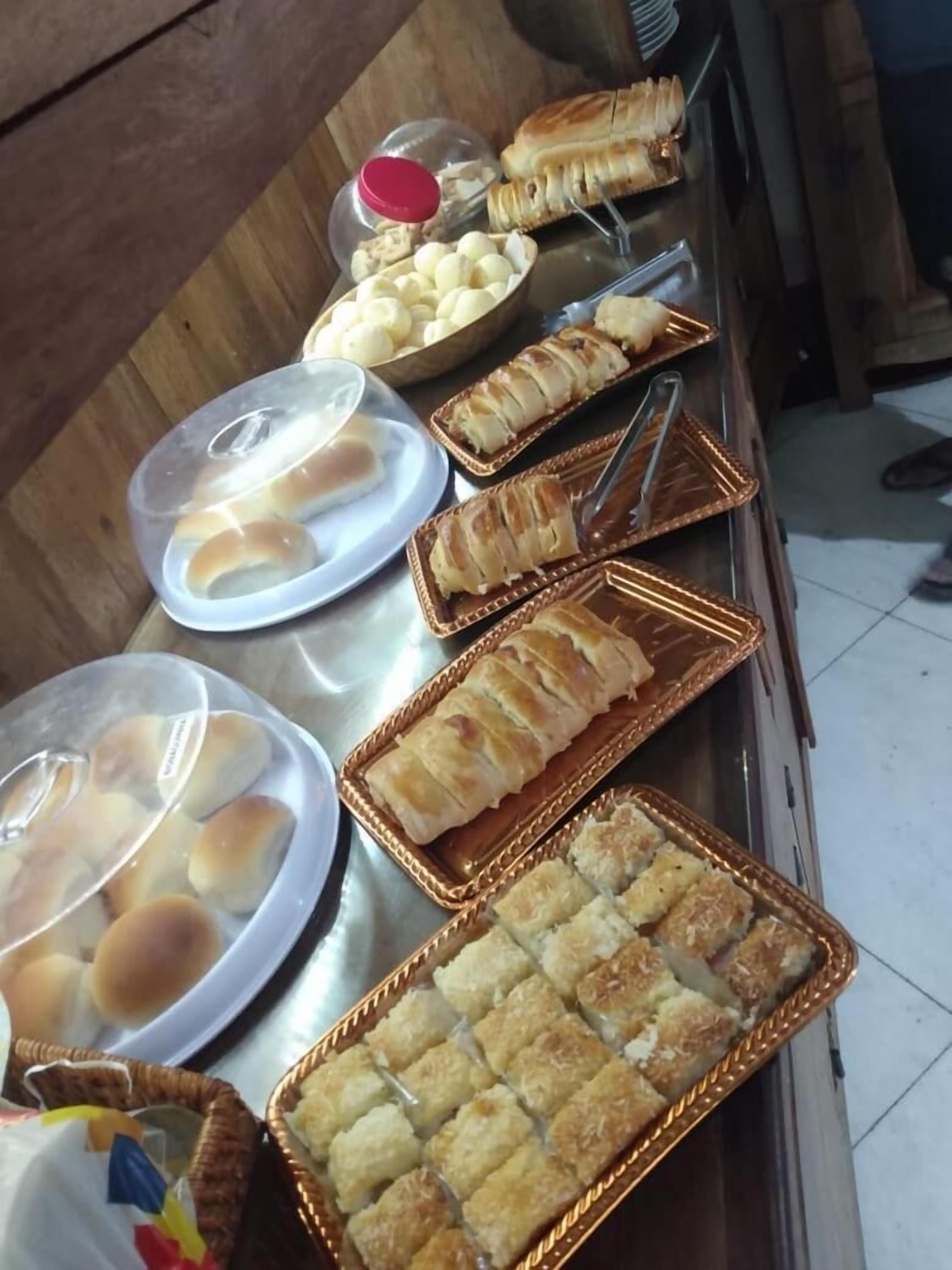 A buffet table with various baked goods including bread rolls, pastries, and a tray of golden-brown squares.