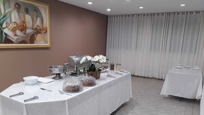 Spiseområde med et langt bord dækket til et måltid, en buffet og et maleri på væggen.