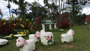 A garden with decorative sheep statues, a small table with a white picket fence, and lush greenery. - Phunaya Resort (Khao Kho)