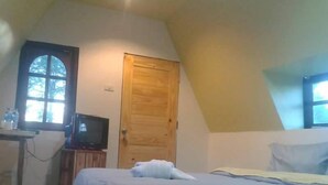 A bedroom with a bed, a wooden door, a television on a stand, and a window. - Phunaya Resort (Khao Kho)