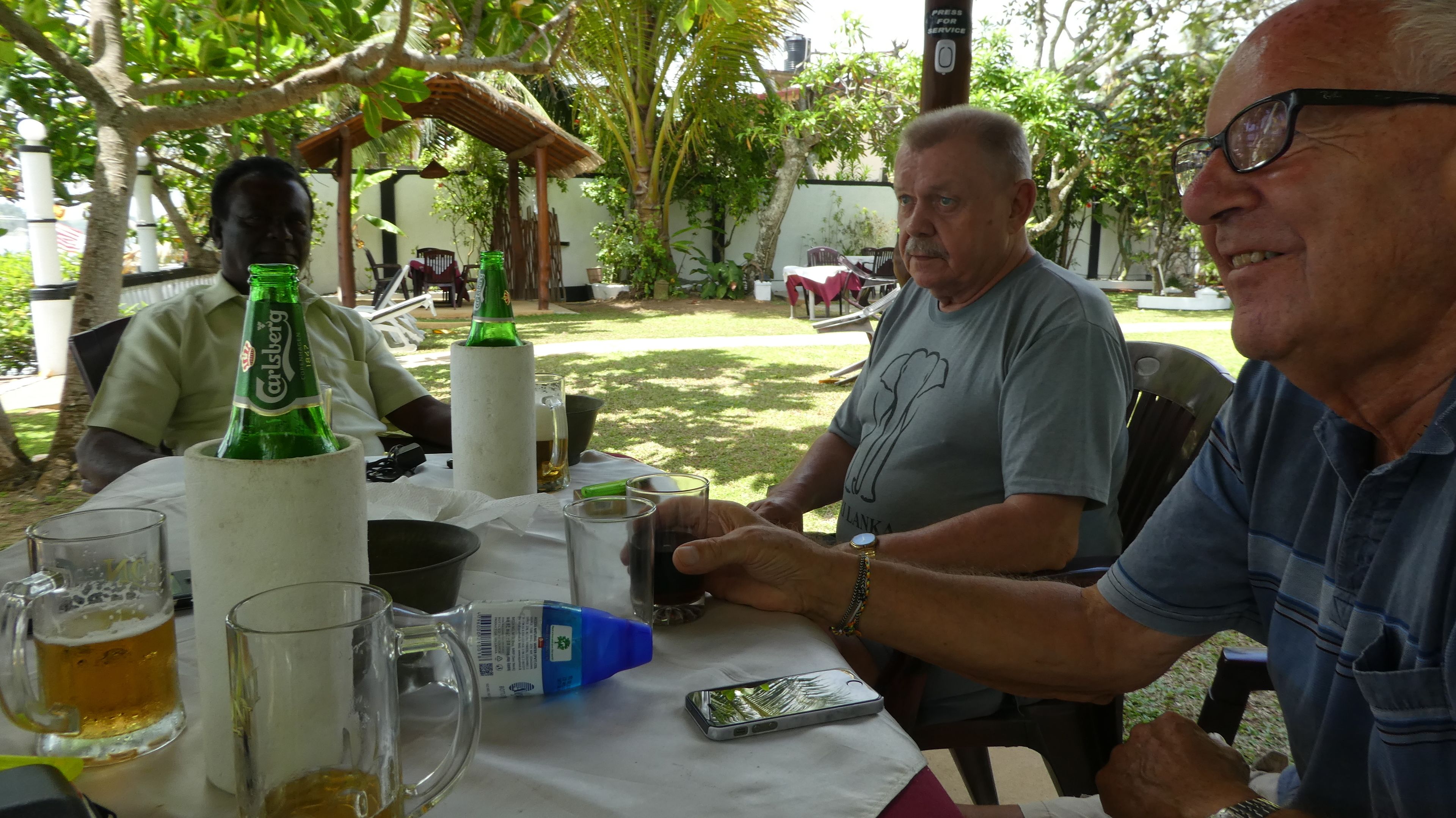 A table with bottles, glasses, and a mobile phone.