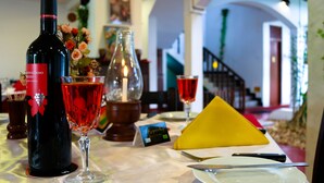 A table with a bottle of red wine, a glass of red wine, a yellow napkin, a knife, and a plate. - Hotel Hemadan (Aluthgama)