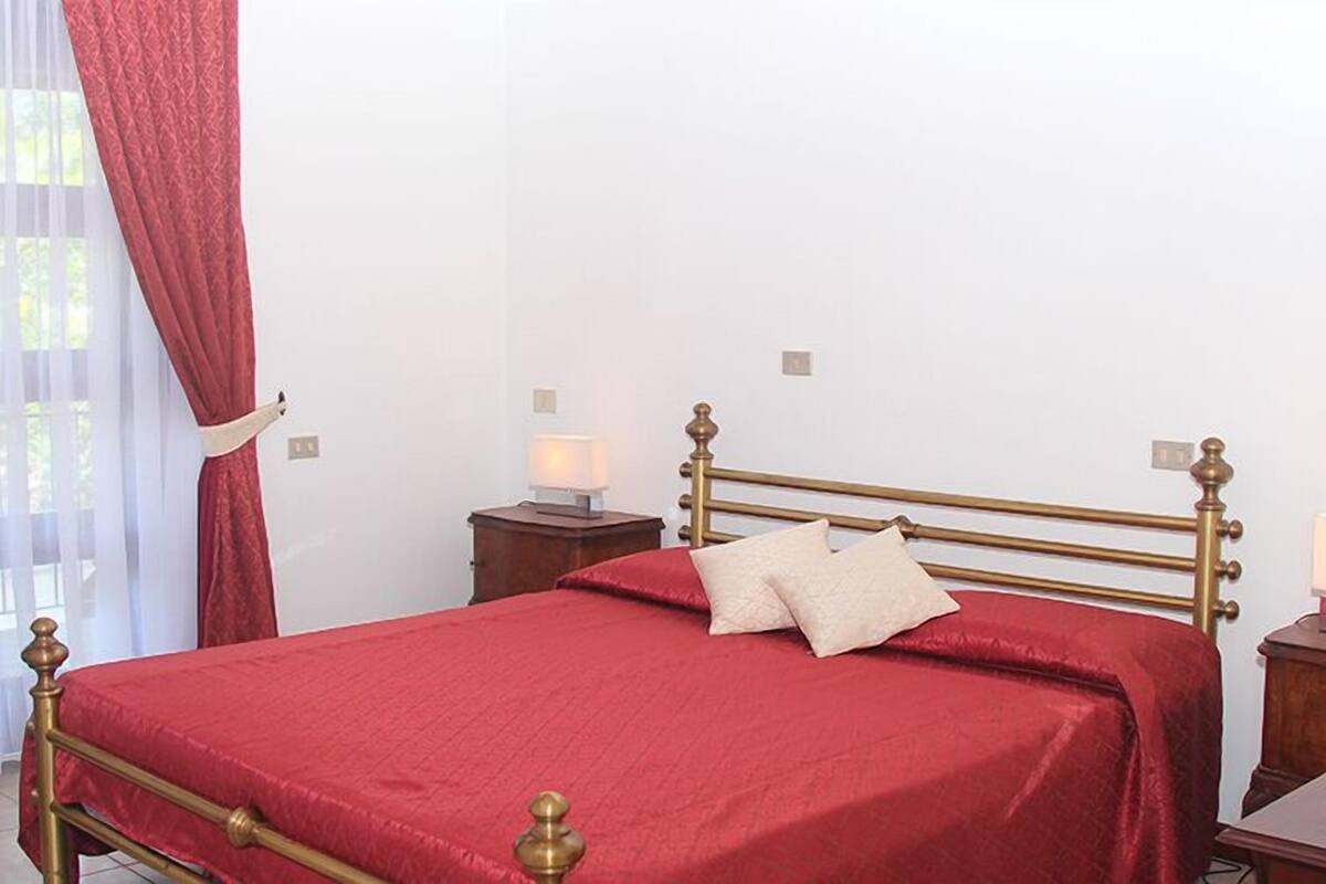 A neatly arranged bedroom with a single bed, two bedside tables, and a window with sheer curtains.