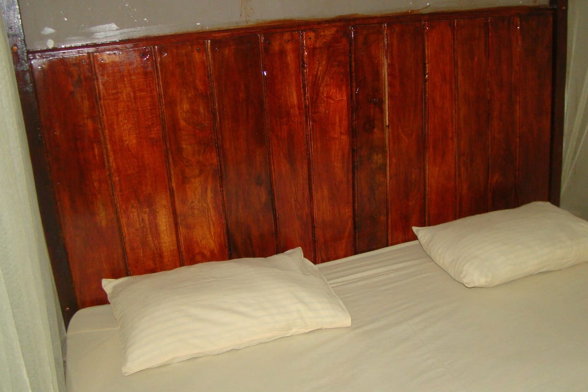 A bed with a wooden headboard and two pillows.