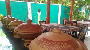 A dining area with terracotta pots, a checkered tablecloth, and a green wall. - Hotel Camorich (Thissamaharama)