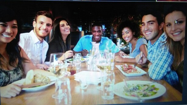 A group of people dining at a restaurant with a wooden table and various dishes. - Hotel Camorich (Thissamaharama)