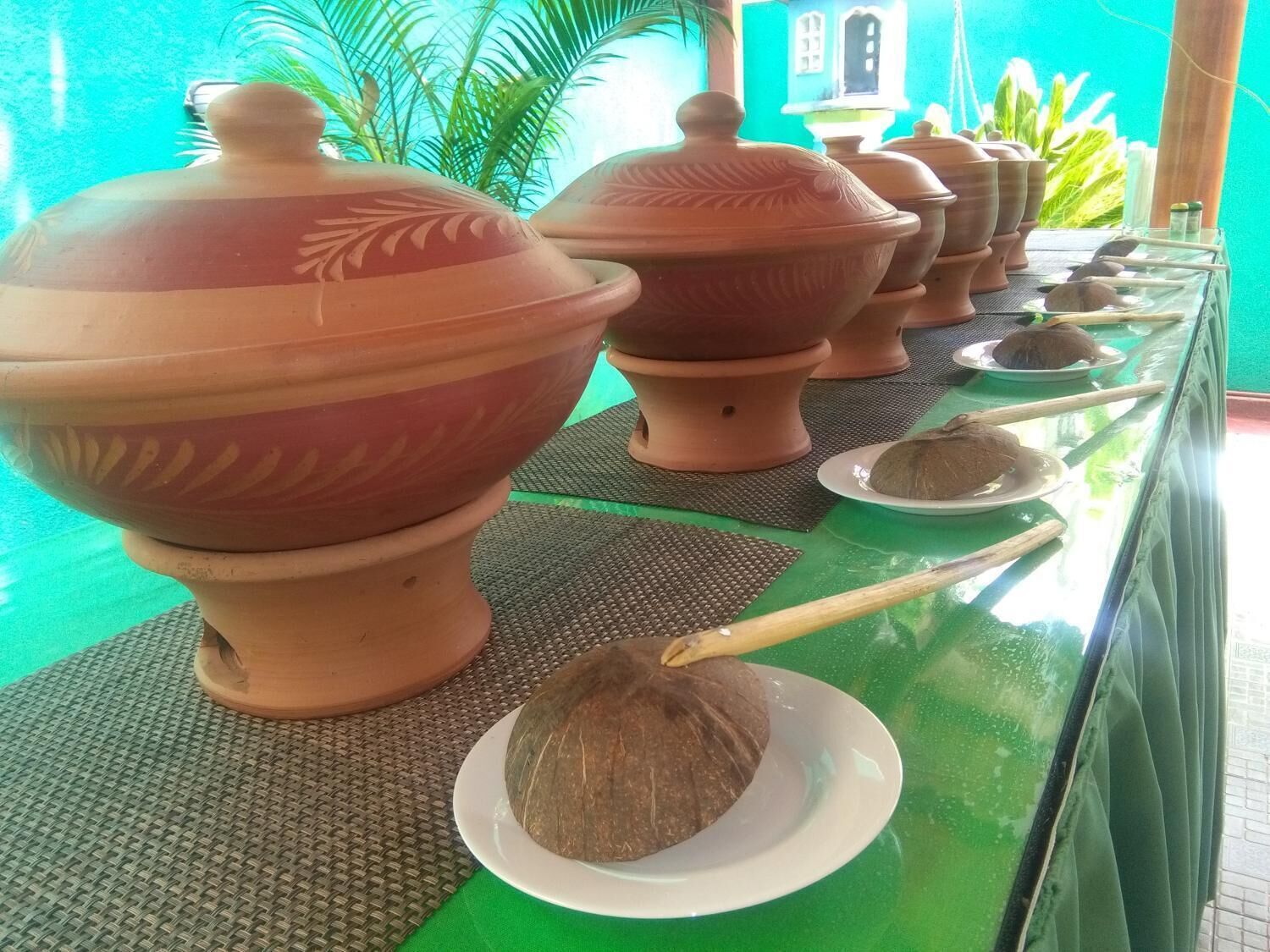 Terracotta pots with lids and a coconut on a table.
