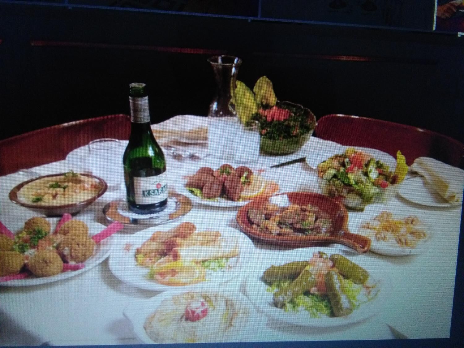 Una mesa de comedor dispuesta con diferentes platos, una botella de vino y un florero con flores.