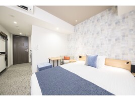 Een hotelkamer met een bed, een bureau, een stoel en een klein tafeltje.
