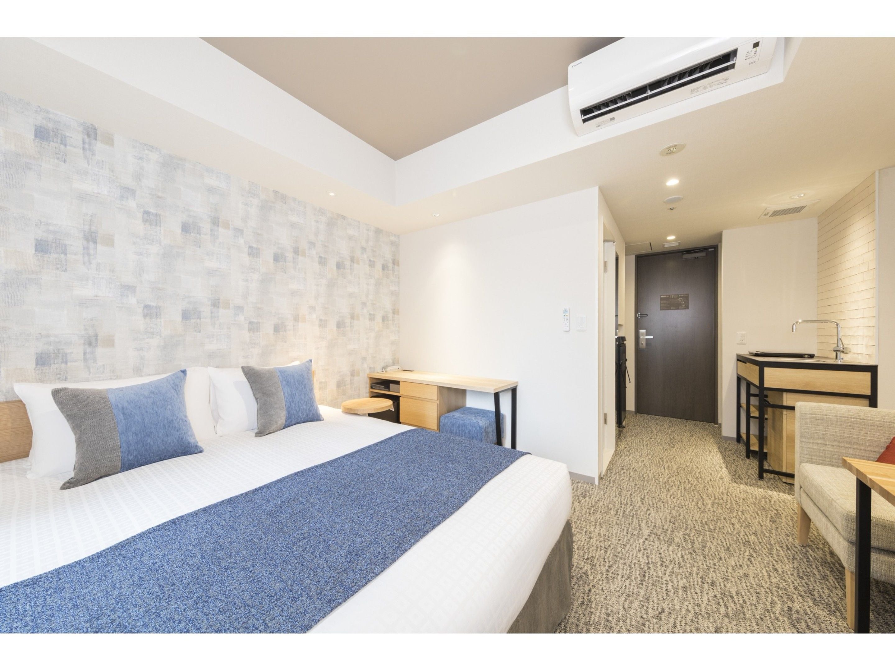 A modern hotel room with a large bed, a desk, and a shower area.