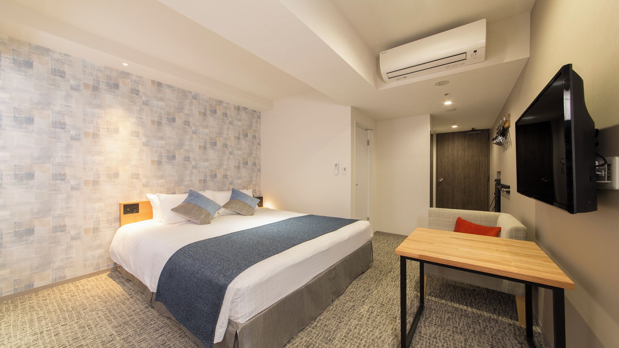 Une chambre d’hôtel équipée d’un lit, d’un bureau, d’une télévision et d’un appareil de climatisation.
