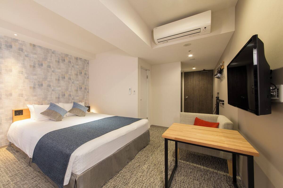 Ein Hotelzimmer mit einem Bett, einem Schreibtisch, einem Fernseher und einer Klimaanlage.