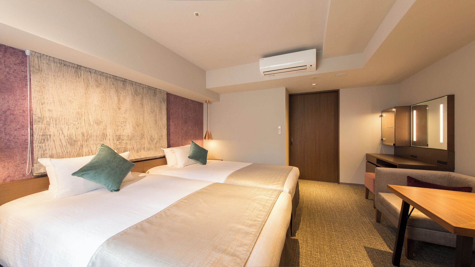 Une chambre d’hôtel avec deux lits, un bureau, une chaise, un appareil de climatisation et un miroir.