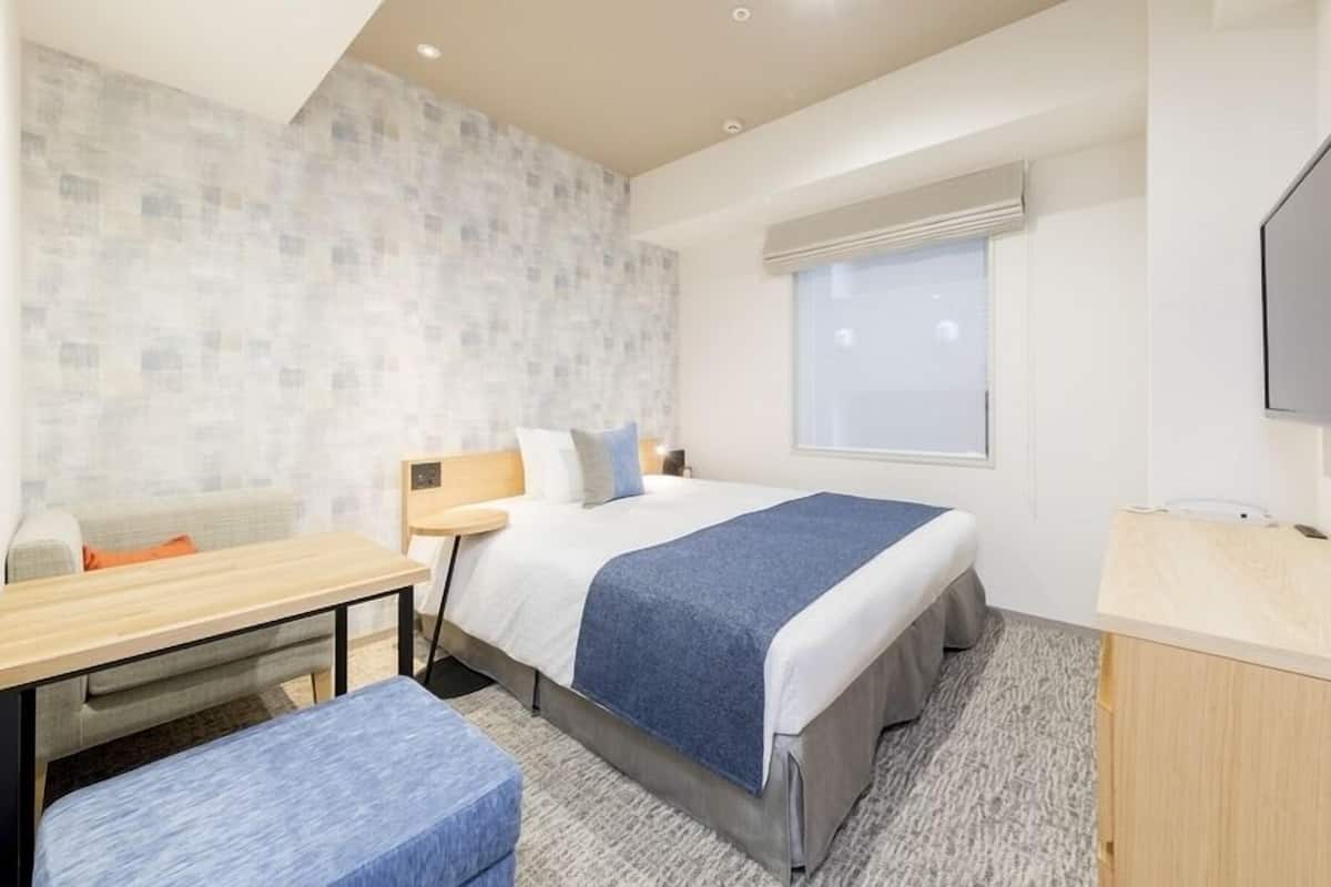Una habitación de hotel con una cama, un escritorio, una silla, un televisor y una ventana.