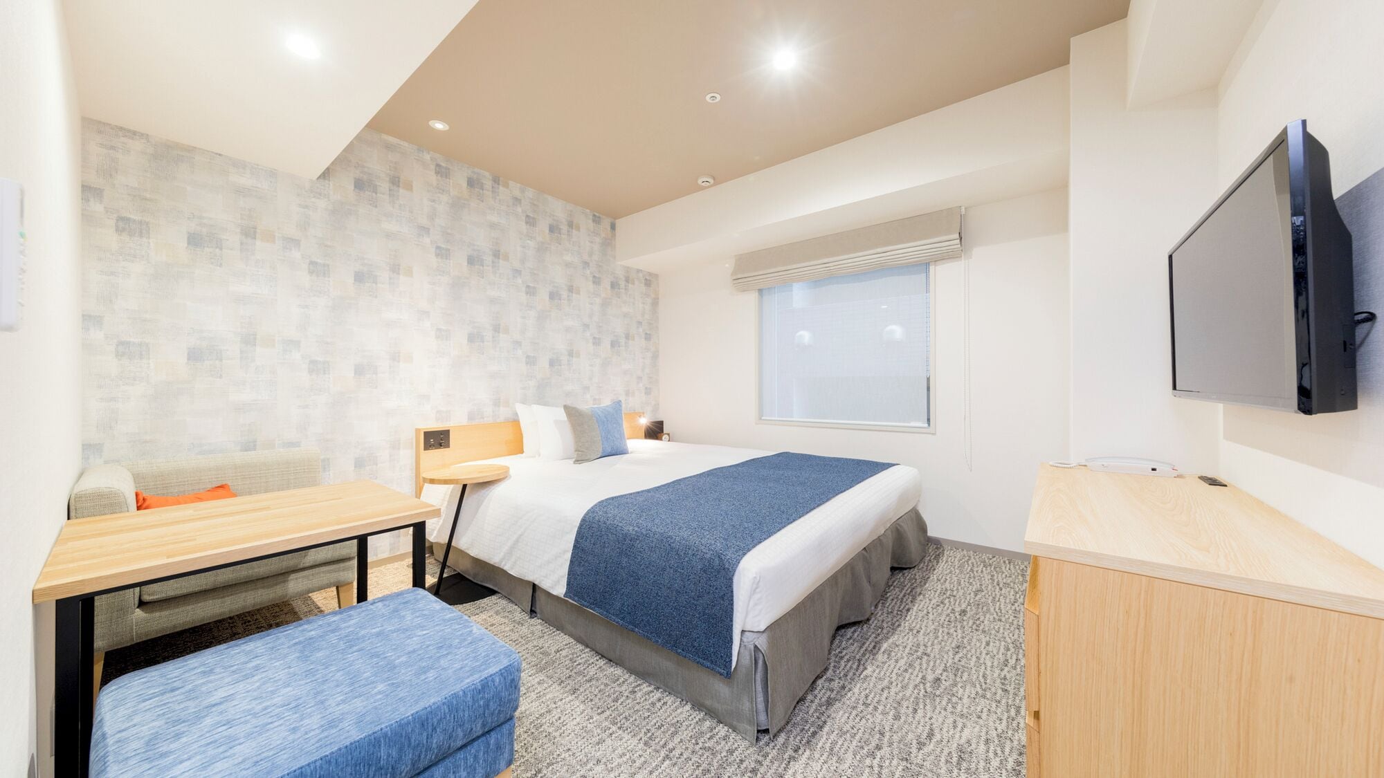 Une chambre d’hôtel avec un lit, un bureau, une chaise, une télévision et une fenêtre.
