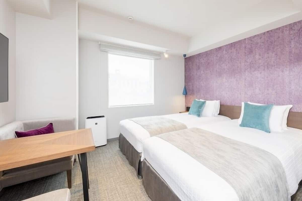 Una habitación de hotel con una cama grande, un escritorio, una silla y una ventana.