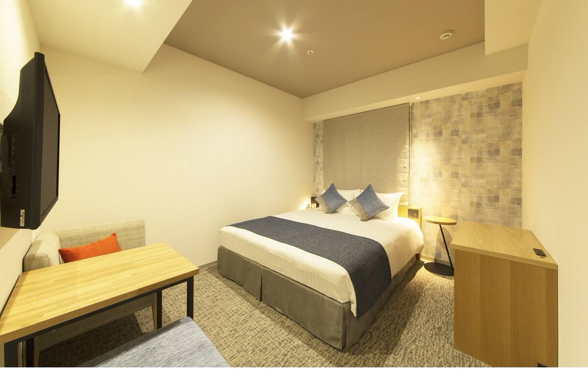 Ein modernes Hotelzimmer mit Bett, Nachttisch und Schreibtisch.