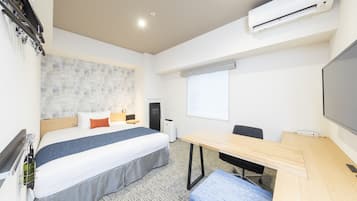 Une chambre d’hôtel équipée d’un lit, d’un bureau, d’une chaise, d’un climatiseur, d’un écran de projection et d’une fenêtre.