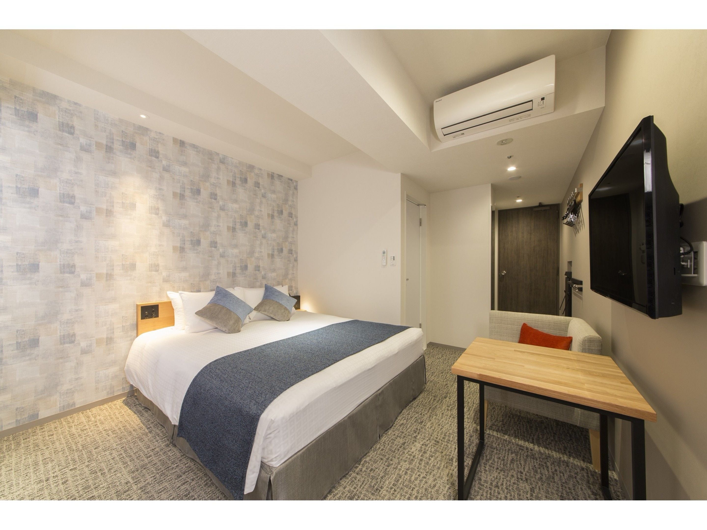 A modern hotel room with a large bed, a desk, and a TV.