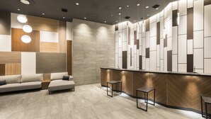 Un espace d’accueil moderne comprenant un comptoir de réception en bois, un canapé et deux petites tables.